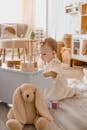 A cute toddler playing joyfully in a stylish and cozy nursery setting with soft toys and wooden blocks.